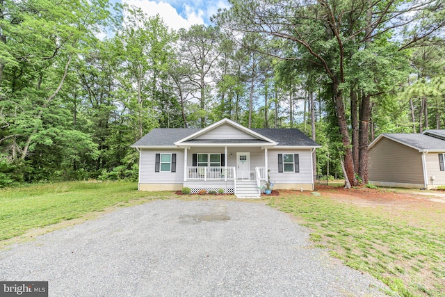 309 N Glebe Rd, Montross, VA 22520 - view of front of house with covered porch, roof with shingles, a front yard, and view of wooded area