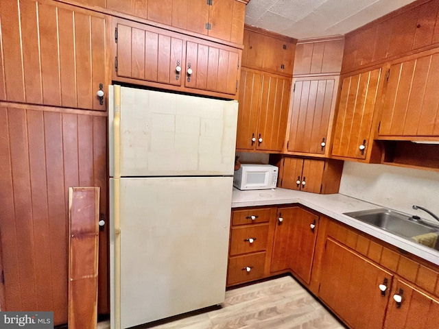 203 N Cedar St, Lititz, PA 17543 - kitchen with white appliances, brown cabinetry, a sink, light countertops, and light wood-style flooring