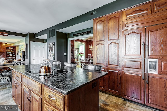 7140 Poole Jones Rd, Frederick, MD 21702 - kitchen with black electric cooktop, dark countertops, a kitchen island, brown cabinetry, and a ceiling fan