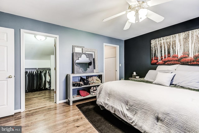 7140 Poole Jones Rd, Frederick, MD 21702 - bedroom featuring wood finished floors, a walk in closet, a closet, ceiling fan, and baseboards