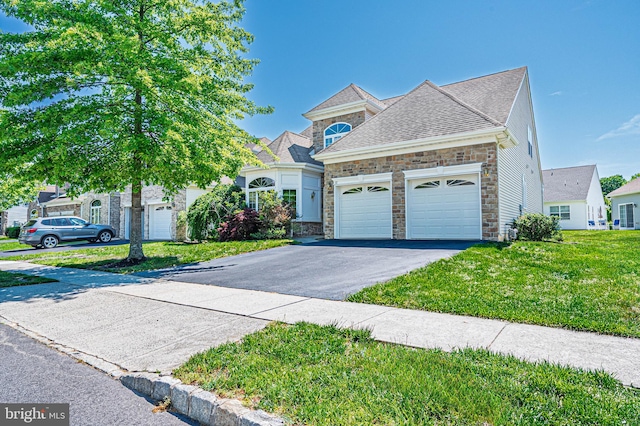 view of front of property with stone siding, driveway, an attached garage, and a front lawn