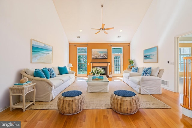 living area featuring plenty of natural light, wood finished floors, ceiling fan, high vaulted ceiling, and a fireplace