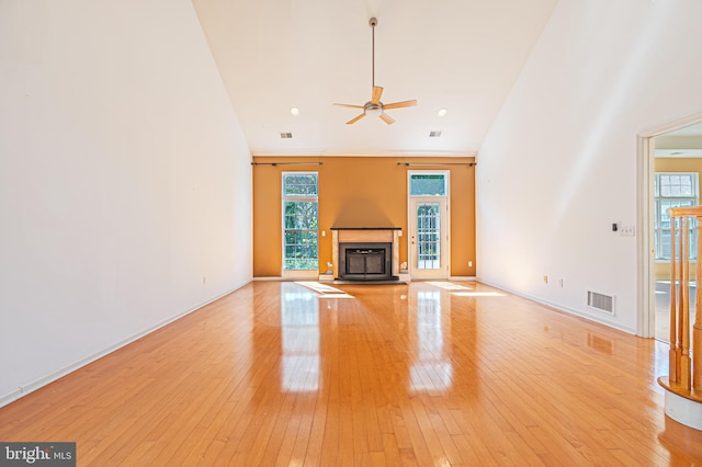 unfurnished living room featuring ceiling fan, light wood-style flooring, a glass covered fireplace, and baseboards