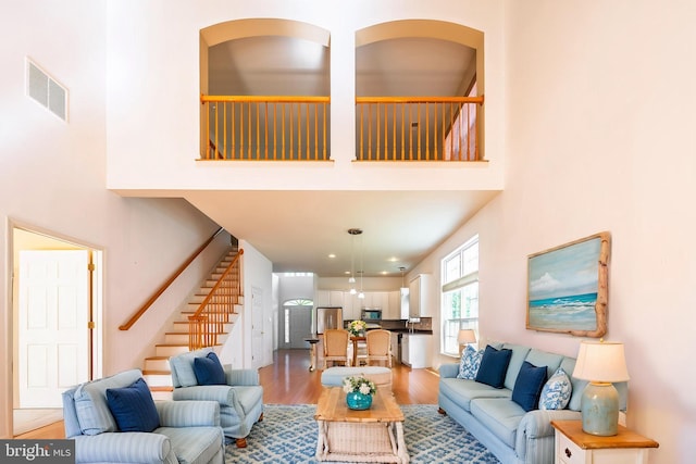 living area with light wood-style floors, stairway, and a towering ceiling
