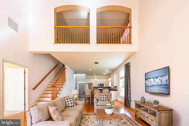 living area featuring stairs, light wood-type flooring, and a high ceiling