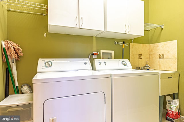 laundry area with independent washer and dryer and cabinet space
