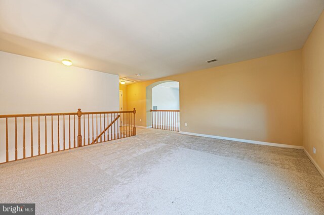 spare room featuring arched walkways, carpet flooring, and baseboards