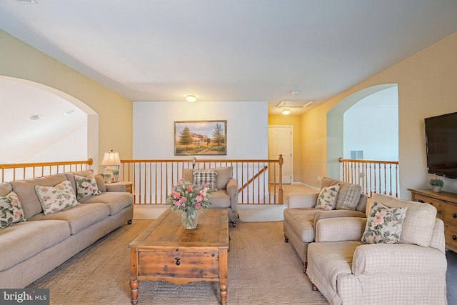 carpeted living area featuring arched walkways