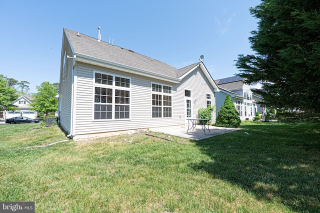 rear view of property with a patio area, a yard, and a shingled roof
