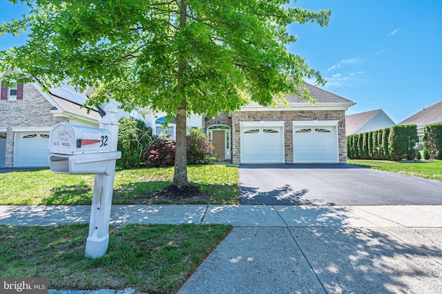 view of front of property featuring stone siding, driveway, a garage, and a front lawn