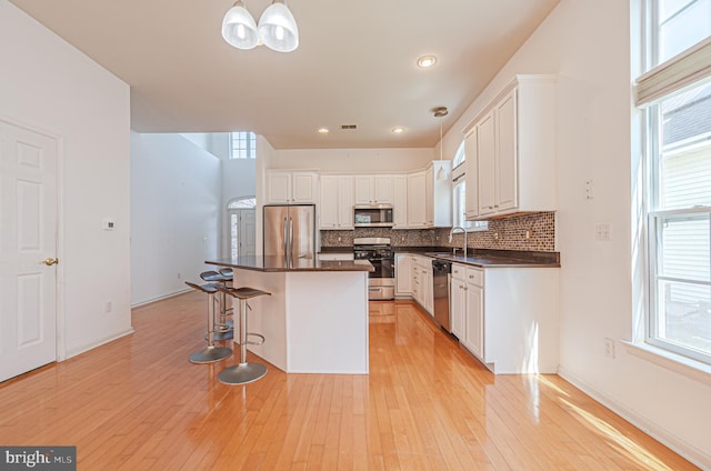 kitchen with stainless steel appliances, dark countertops, tasteful backsplash, a breakfast bar area, and recessed lighting