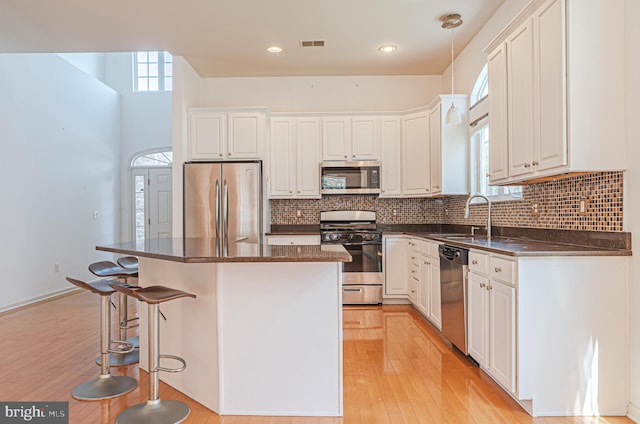 kitchen featuring stainless steel appliances, a sink, a kitchen island, light wood-style flooring, and recessed lighting