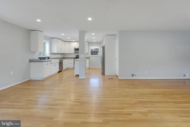 1305 S Buchanan St S, Arlington, VA 22204 - kitchen with stainless steel appliances, white cabinetry, open floor plan, light wood finished floors, and baseboards