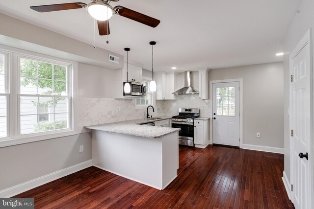 3411 Roselawn Ave, Baltimore, MD 21214 - kitchen featuring appliances with stainless steel finishes, wall chimney exhaust hood, a sink, a peninsula, and white cabinetry