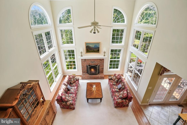 living area featuring a towering ceiling, baseboards, ceiling fan, and a fireplace