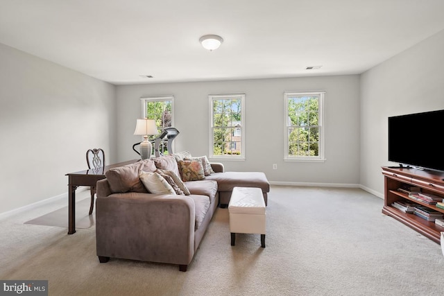 living area featuring light carpet, plenty of natural light, and baseboards