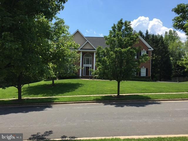 view of property hidden behind natural elements featuring a front lawn