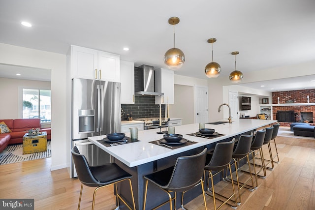 36 Gettysburg Ln, Newtown, PA 18940 - kitchen with appliances with stainless steel finishes, a sink, open floor plan, wall chimney range hood, and light wood-style flooring
