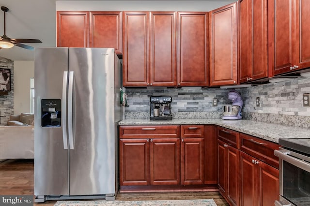 kitchen with appliances with stainless steel finishes, ceiling fan, backsplash, and light stone counters