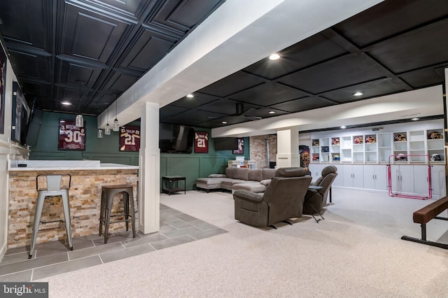 carpeted living room with bar, recessed lighting, a decorative wall, and tile patterned floors