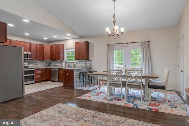 kitchen with stainless steel appliances, dark wood finished floors, backsplash, a chandelier, and hanging light fixtures