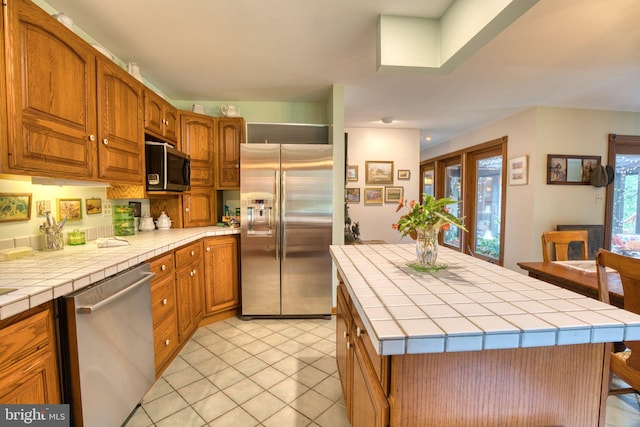 3012 Duncan Rd, White Hall, MD 21161 - kitchen with stainless steel appliances, tile counters, and brown cabinetry