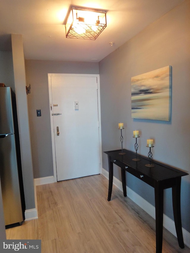 foyer with light wood-style flooring and baseboards