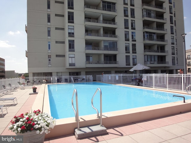 community pool with fence and a patio area