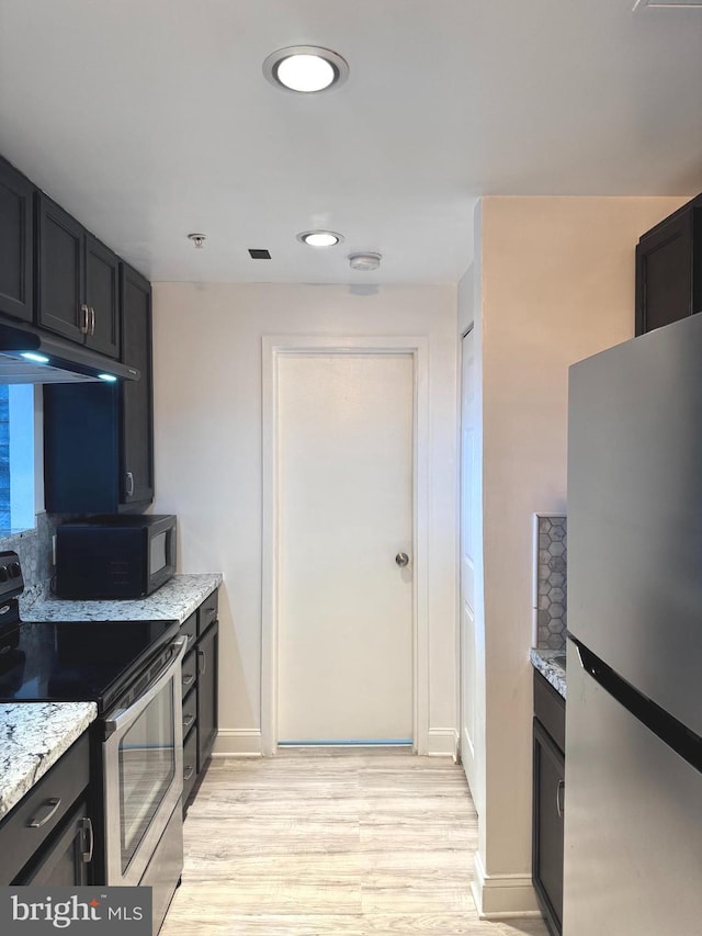 kitchen with stainless steel appliances, light wood finished floors, and light stone countertops