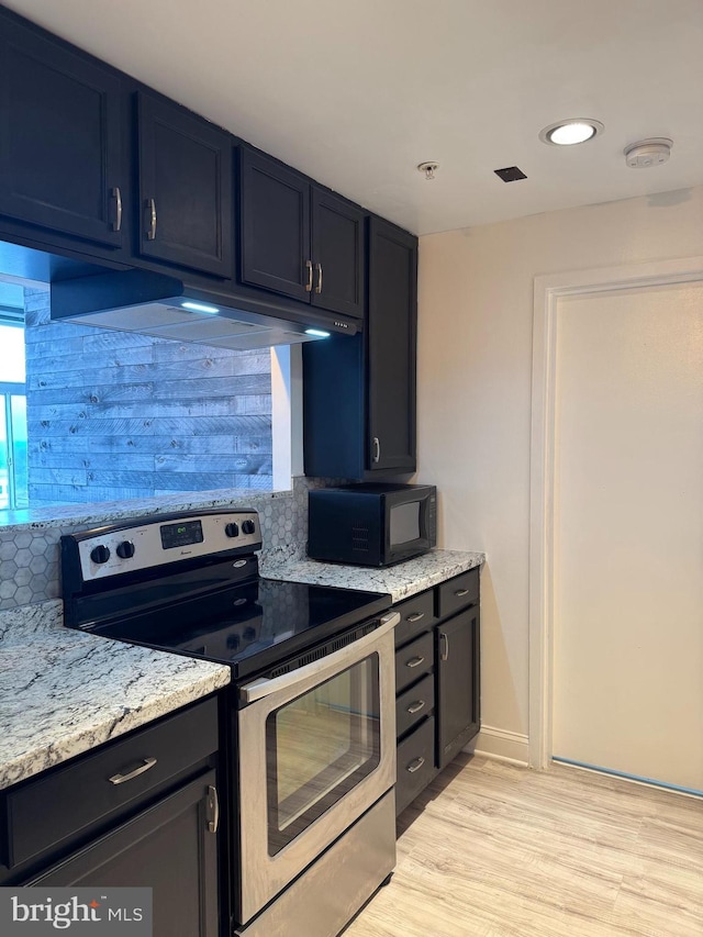 kitchen with stainless steel range with electric cooktop, black microwave, under cabinet range hood, light wood-style flooring, and backsplash