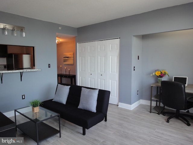 living room featuring light wood-style floors, a desk, and baseboards