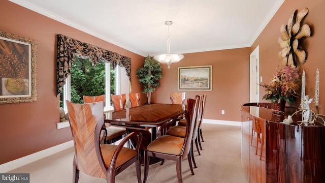 dining room with ornamental molding, baseboards, and light colored carpet