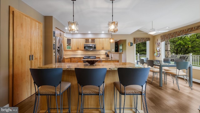 kitchen with appliances with stainless steel finishes, a sink, wood finished floors, glass insert cabinets, and recessed lighting