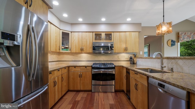 kitchen featuring appliances with stainless steel finishes, a sink, dark wood-style floors, light stone counters, and recessed lighting