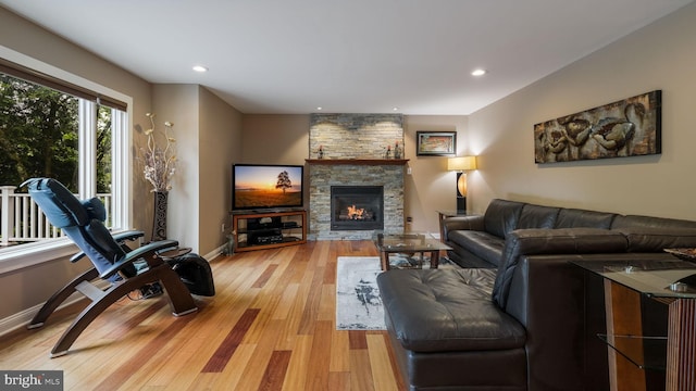 living area with light wood-type flooring, a fireplace, baseboards, and recessed lighting
