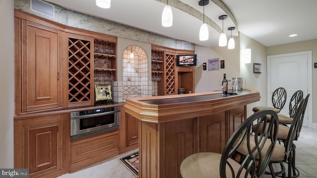 indoor dry bar with light tile patterned flooring, stainless steel oven, and decorative light fixtures