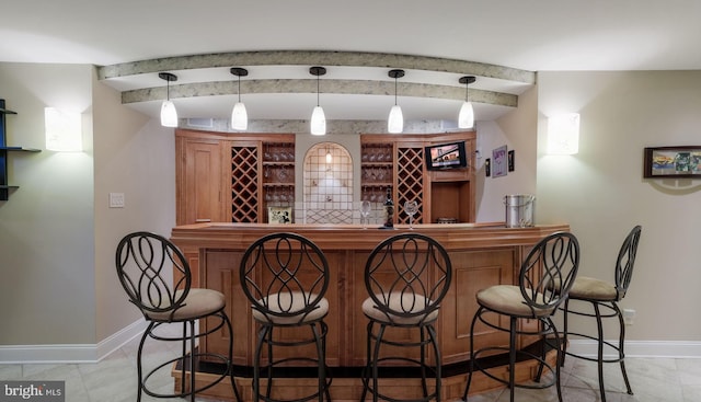 indoor bar with baseboards, beam ceiling, tile patterned flooring, and decorative light fixtures