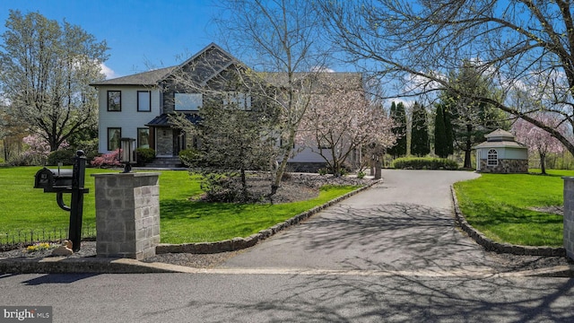 view of front of property featuring a front yard, stone siding, and driveway