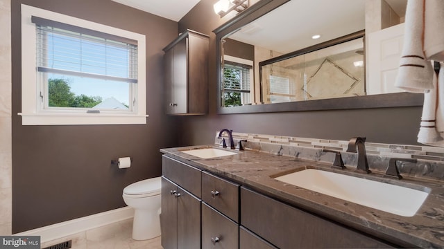 full bath with a stall shower, baseboards, toilet, and double vanity