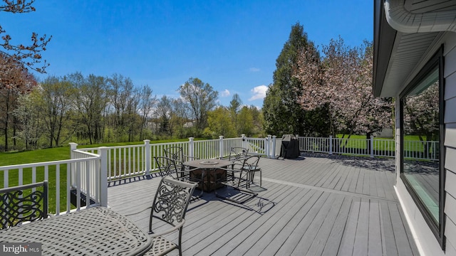 wooden deck featuring a lawn and outdoor dining area