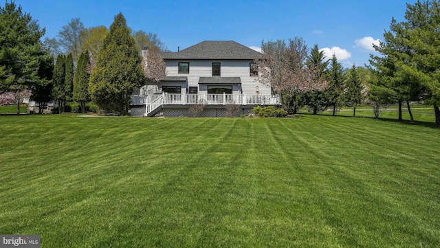 back of house with a deck, a lawn, and a chimney