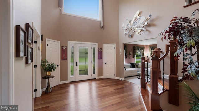 foyer entrance featuring a high ceiling, wood finished floors, and baseboards
