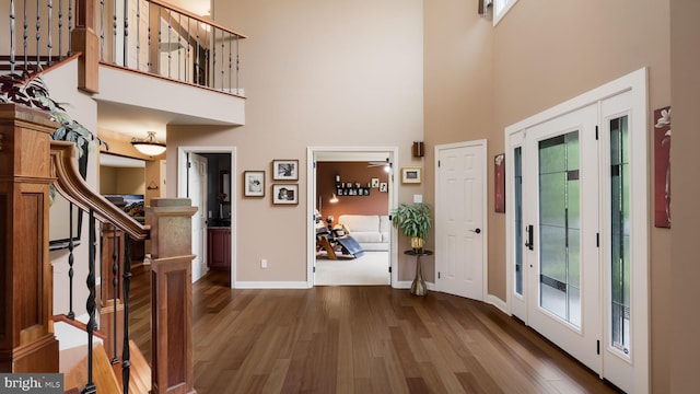 foyer featuring a high ceiling, wood finished floors, baseboards, and stairs