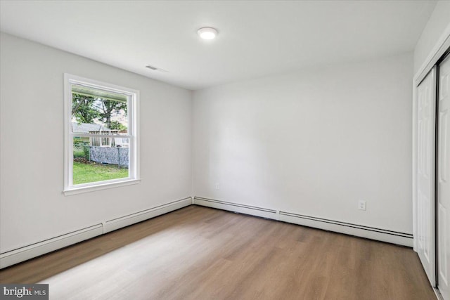 119 Oaktree Dr, Levittown, PA 19055 - unfurnished bedroom with wood finished floors, a closet, and a baseboard heating unit