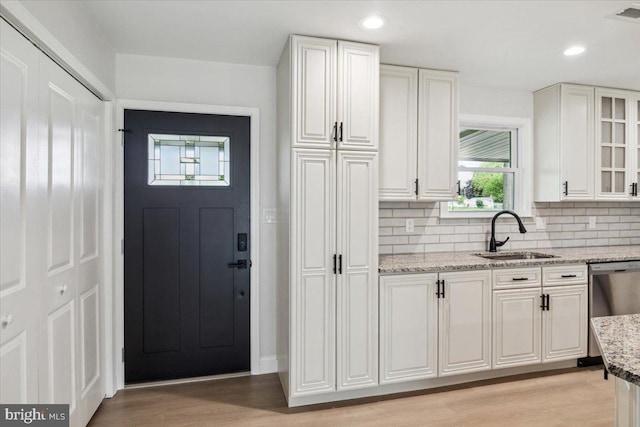 119 Oaktree Dr, Levittown, PA 19055 - kitchen featuring a sink, stainless steel dishwasher, white cabinets, tasteful backsplash, and light stone countertops