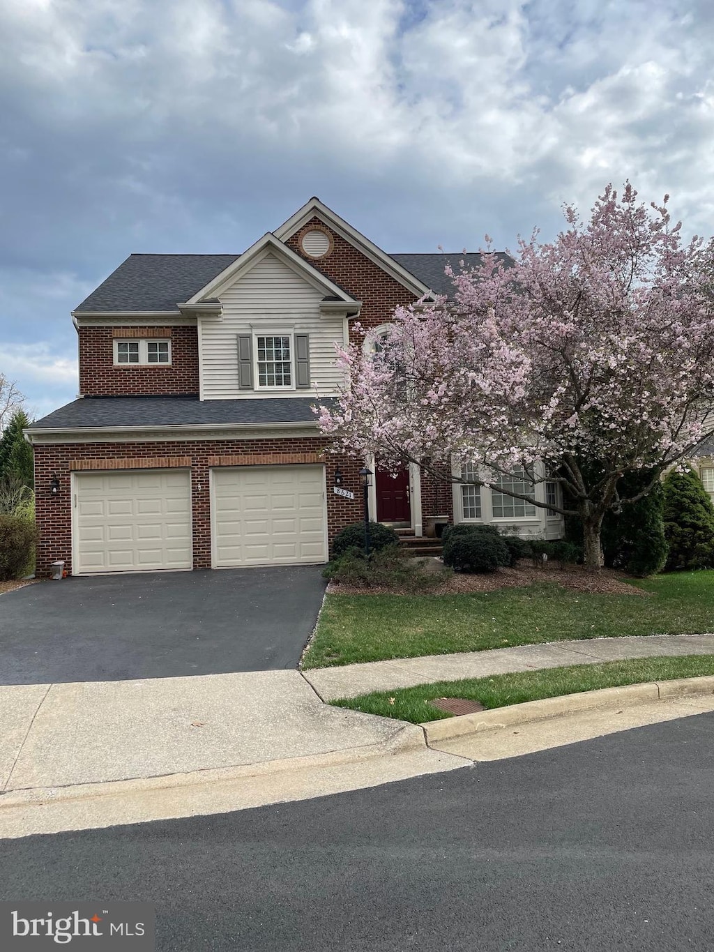 view of front of house featuring an attached garage, driveway, and brick siding