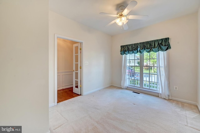 carpeted spare room featuring a ceiling fan and baseboards