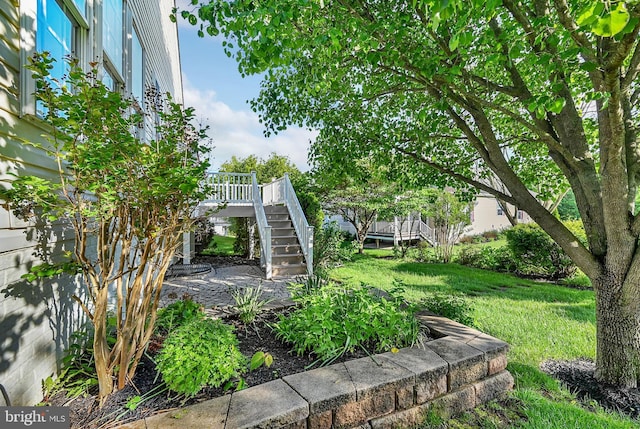view of grassy yard with stairs and a deck