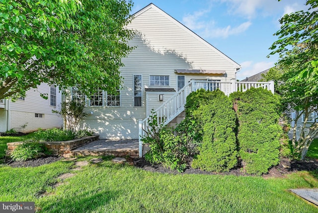 back of property with stairway, a wooden deck, and a yard