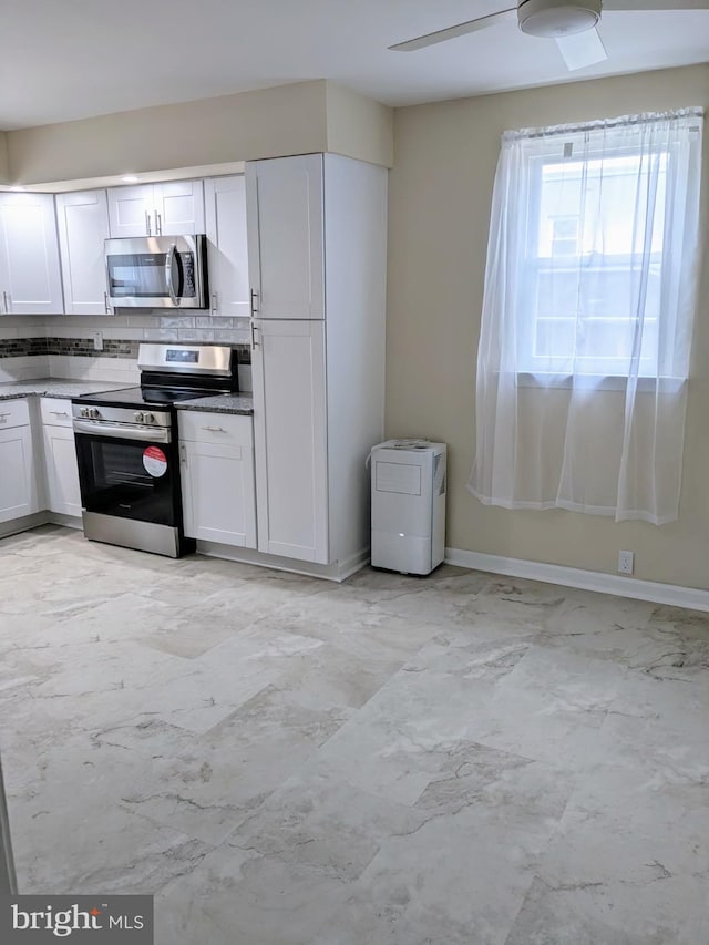 kitchen with stainless steel appliances, decorative backsplash, white cabinetry, baseboards, and light marble finish floors